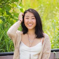 UMN pre-health student Elizabeth Vue smiling in the sunlight near tall grass 