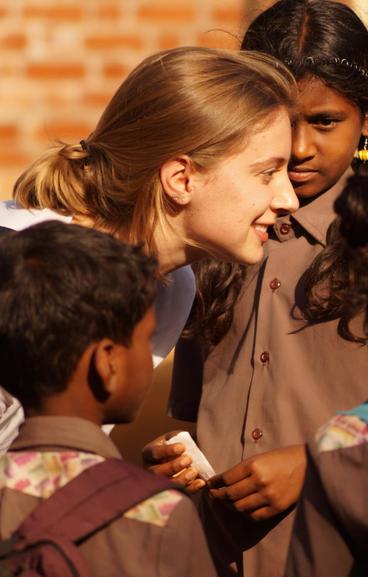 A student talks to some children in India